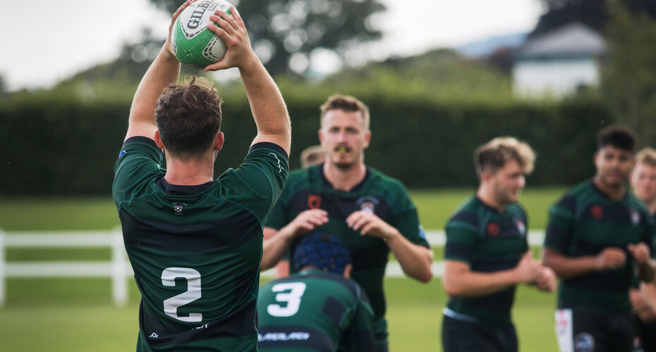A rugby player holding the ball over his head, about to throw it to his teammate